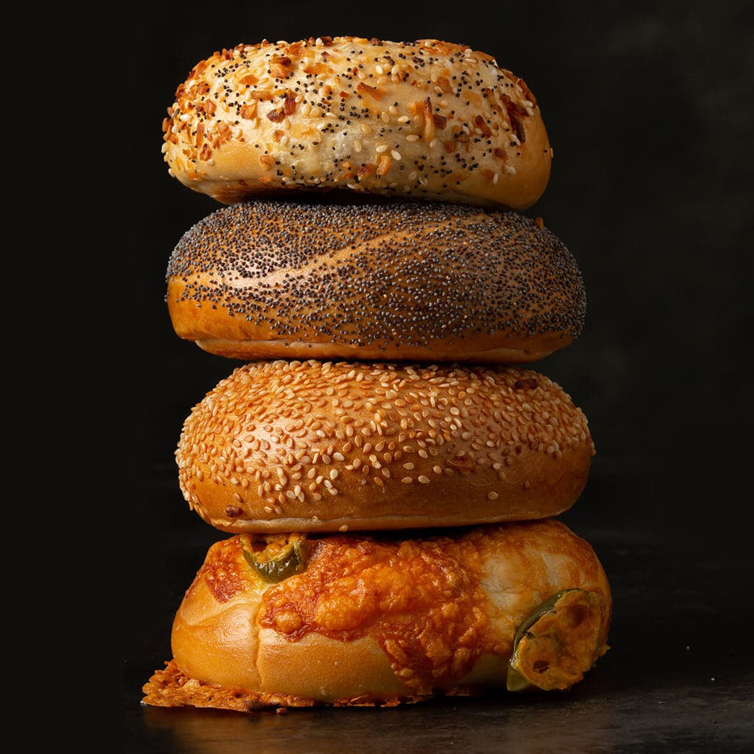 A stack of four All Star bagels: everything, poppy, sesame and jalapeño cheddar